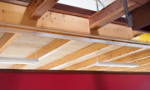 Detalle constructivo de forjado de madera con vigas expuestas y paneles aislantes.