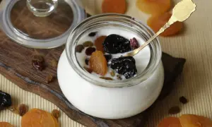 Jogurt z suszonymi owocami i złotą łyżeczką – idealne szybkie śniadanie na ciepło.