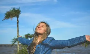 Joven con los brazos extendidos, disfrutando del aire libre, como en las lao tse frases sobre la libertad y la naturaleza.