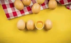 Uova su sfondo giallo, una rotta mostra il tuorlo. Quante uova si possono mangiare al giorno?