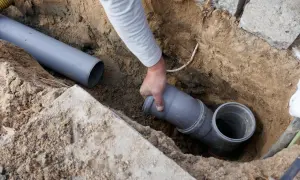 Hand verbindet ein Rohrstück mit einem Abzweig. Dies ist Teil der Installation, um die wasserleitung frostsicher isolieren zu können.