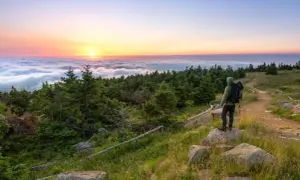 Wanderer genießt Sonnenaufgang über Wolkenmeer. Auf dem Brocken kann man wandern, die Natur bestaunen und den Ausblick genießen.