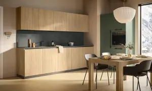 Cucina moderna con mobili in legno chiaro e pensili alti. La zona pranzo è apparecchiata, con una vista panoramica innevata dalla finestra. L'altezza dei mobili cucina è ben studiata per funzionalità ed estetica.