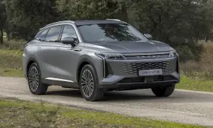Szary OMODA 9 na drodze leśnej. Nowoczesny SUV z charakterystycznym grillem i światłami LED.