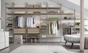 Una cabina armadio mansarda bassa, con scaffali in legno e metallo, ospita abiti ordinati e accessori.