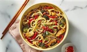 Pyszny makaron udon z kurczakiem, brokułami i papryką w sosie. Danie posypane sezamem i szczypiorkiem. Idealne na obiad, a jego makaron udon kcal jest zbilansowany.