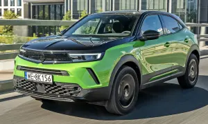 Nowy Opel Mokka w jaskrawej zieleni, z czarnym dachem, pędzi po drodze. Sprawdź jego atrakcyjną opel mokka cena!