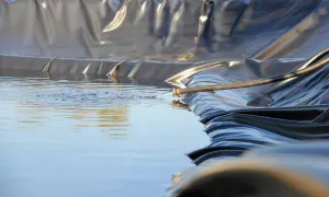 Wasser fließt aus einem Schlauch in einen neu angelegten Folienteich.