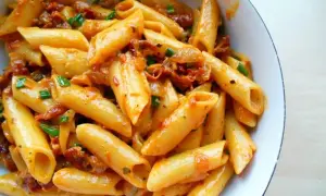 Penne z sosem z suszonych pomidorów, czosnku i ziół, posypane szczypiorkiem. Pyszne danie, które zachwyci każdego miłośnika makaronu.