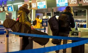 Osoby z bagażem sportowym Ryanair czekają w kolejce na lotnisku.