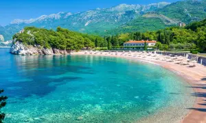 Malownicza zatoka z piaszczystymi plażami w Czarnogórze. Turkusowa woda, zielone wzgórza i biały budynek hotelu tworzą idylliczny krajobraz.