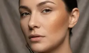 Kobieta z pędzlem do makijażu aplikuje bronzer, tworząc ciepły, promienny wygląd.