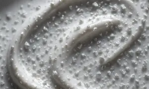 Biały krem z drobinkami, które mogą być dwutlenkiem tytanu, tworzy falisty wzór.