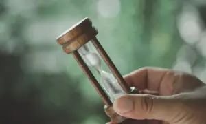 Main tenant une sablier, symbolisant le temps qui passe et le délai de grâce pour un crédit consommation.