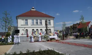 Uroczystość religijna na rynku w **Borku Wielkopolskim**. Kapłan odprawia mszę, towarzyszą mu ministranci i wierni.