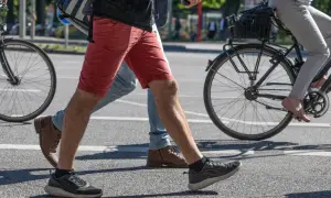 Ludzie przechodzą przez pasy, jeden na rowerze, drugi pieszo. Czy jazda na rowerze odchudza brzuch? To pytanie zadaje sobie wielu.