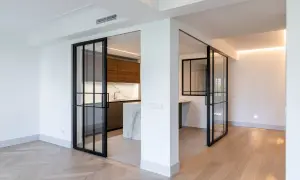 Puertas correderas de cristal negro separan la cocina moderna. Se planea poner baldas entre dos paredes para maximizar el espacio.
