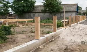 Szalunek pod ogrodzenie w budowie. Betonowy fundament, drewniane słupki i konstrukcja podłogi domu.