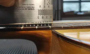 Ajustando la altura de las cuerdas de una guitarra flamenca con una regla de acción.