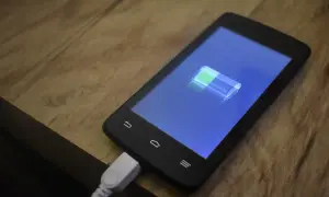 Smartfon podłączony do ładowania, na ekranie ikona baterii. Dowiedz się, jak włączyć szybkie ładowanie, by mieć więcej energii!