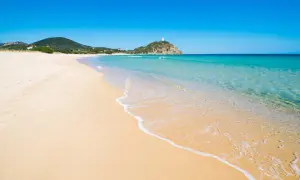 Piękne plaże Cagliari z turkusową wodą i piaszczystym brzegiem. W oddali widać wzgórze z wieżą.