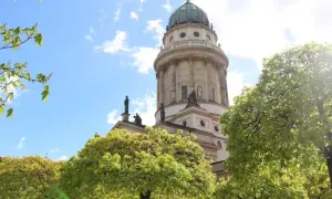 Der Dom in Deutschland, ein majestätisches Bauwerk, ragt hinter blühenden Bäumen in den blauen Himmel.