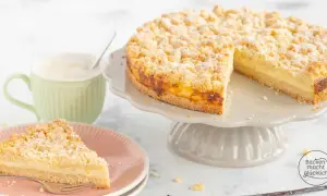 Ein köstlicher Pudding Streuselkuchen mit einer cremigen Füllung und knusprigen Streuseln, daneben eine Tasse Kaffee.