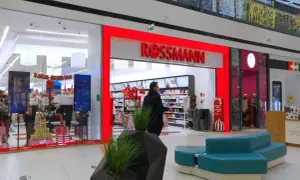 Wejście do drogerii Rossmann w centrum handlowym, z widocznymi promocjami i wystrojem świątecznym.