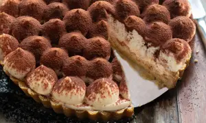 Una deliziosa torta tiramisù, con ciuffi di crema e cacao, pronta per essere gustata.