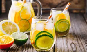Orzeźwiająca biała sangria z plasterkami cytryny, limonki i pomarańczy, podana z lodem w szklankach i dzbanku.