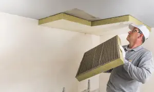 Mann montiert Dämmplatten zur Deckenisolierung innen.