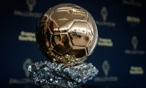 Złota Piłka, symbol triumfu na gali, lśni na tle logo France Football.