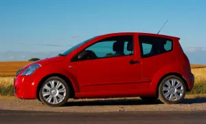 Czerwony Citroen C2 VTR stoi na poboczu drogi, na tle złotego pola i błękitnego nieba.