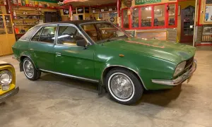 Grön Leyland Princess med svart tak, vit däcksida och kromdetaljer, parkerad i ett garage med retroinredning.