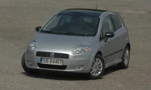 Srebrny Fiat Punto z czarnym dachem i przyciemnianymi szybami, z widocznymi światłami.