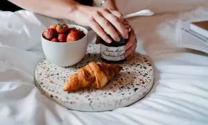 Een croissant, aardbeien en confituur op een dienblad. Perfect om te genieten van eten uit verveling op een luie ochtend.