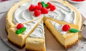 Ein köstlicher american cheesecake, dekoriert mit frischen Himbeeren und Minze, wartet darauf, genossen zu werden.