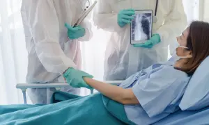 Lekarze w kombinezonach ochronnych wspierają pacjentkę w szpitalu, pokazując jej zdjęcie płuc na tablecie. Nadzieja na powrót do zdrowia dzięki leczeniu, być może z użyciem remdesivir.