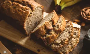Saftiges Bananenbrot, perfekt für ein Bananenbrot Rezept ohne Zucker. Daneben liegen Mandeln und reife Bananen.