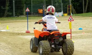 Dziecko w kasku na quadzie uczy się zasad ruchu drogowego na torze. To jego pierwsza karta motorowerowa.