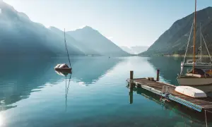 Segelboote am Achensee, ein wahrer Geheimtipp. Berge spiegeln sich im klaren Wasser, ein Steg lädt zum Verweilen ein.