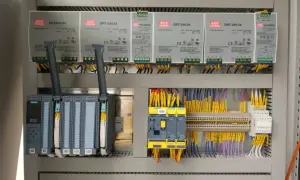 Panel sterowania z zasilaczami MW DRT-240-24, sterownikiem Siemens S7-1500 i żółtymi przewodami. Akpia.