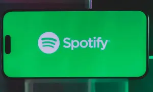 A smartphone displays the Spotify logo on a vibrant green screen, hinting at a free distributor for Spotify.