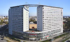 Dom wschodzącego słońca, nowoczesny budynek z charakterystycznym mostem łączącym dwie wieże, z widokiem na miasto.