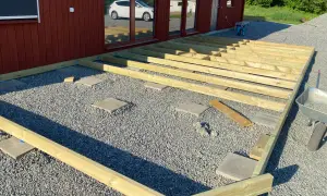 Bygga altan på plattor. Träkonstruktion för altan monteras på grusunderlag med stenplattor som stöd.