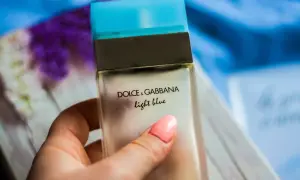 Dłoń z różowym lakierem trzyma buteleczkę perfum Dolce & Gabbana Light Blue.