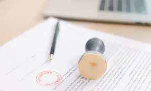 Długopis i pieczątka "APPROVED" na dokumencie. To symbol skutecznej windykacji i finalizacji spraw.