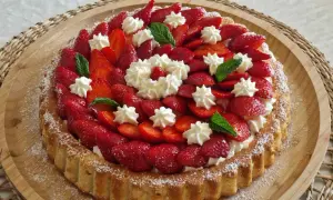 Un délicieux biscuit pour fraisier, garni de fraises fraîches, de crème fouettée et de feuilles de menthe.