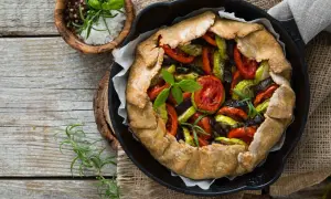 Tarte aux légumes colorée, garnie de tomates, courgettes et aubergines, prête à être dégustée.