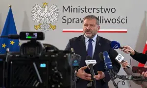 Minister sprawiedliwości przemawia do mediów, otoczony flagami Polski i UE. Dziennikarze zbierają materiał do reportażu o wyroku TSUE.